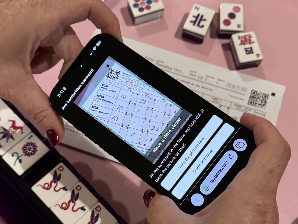Hands holding a phone over the filled-in scorecard to take its picture